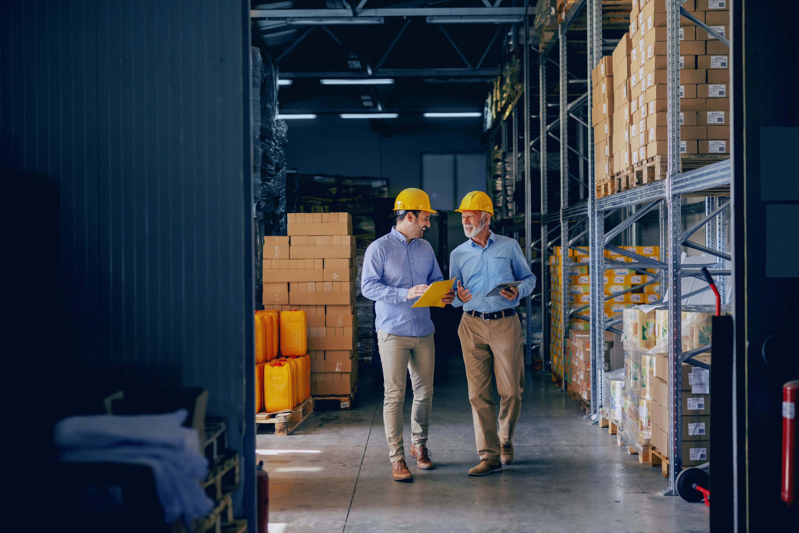 Manufacturing professionals in safety helmets inspecting factory inventory and automated operations