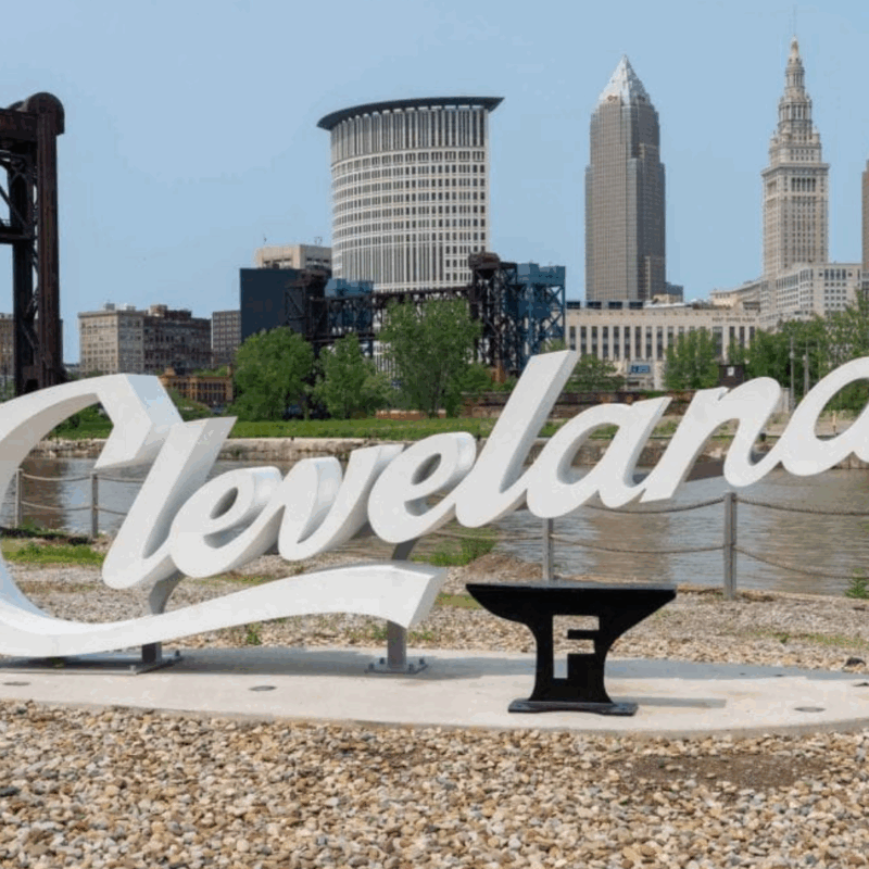Large Cleveland script sign with the Foundry logo along the Cuyahoga river in front of the Cleveland skyline